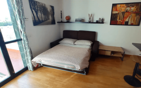 Divano letto aperto in versione matrimoniale nel soggiorno, accanto alla portafinestra del terrazzo