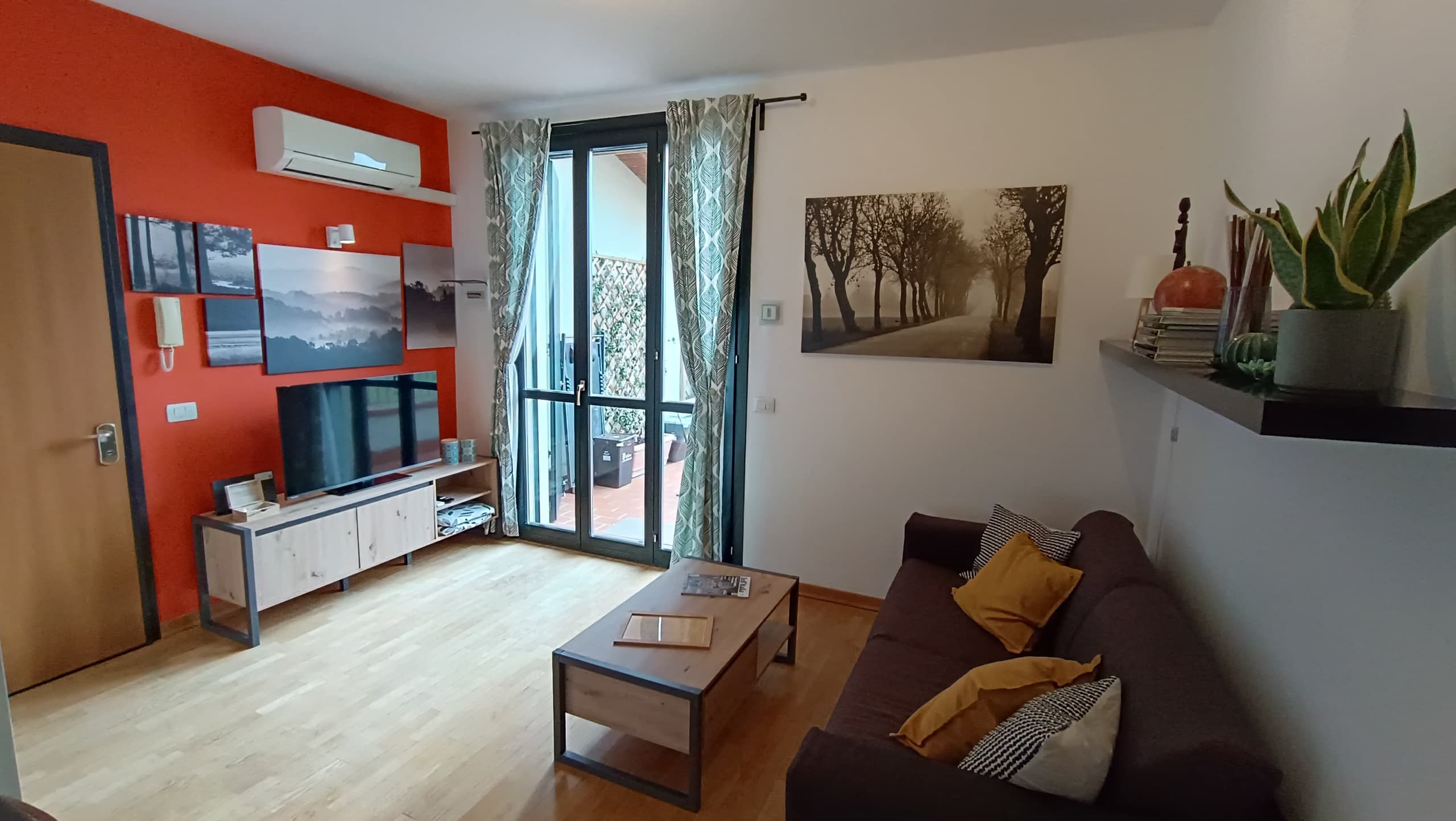 Soggiorno con divano, Smart TV e portafinestra che si apre sul terrazzo